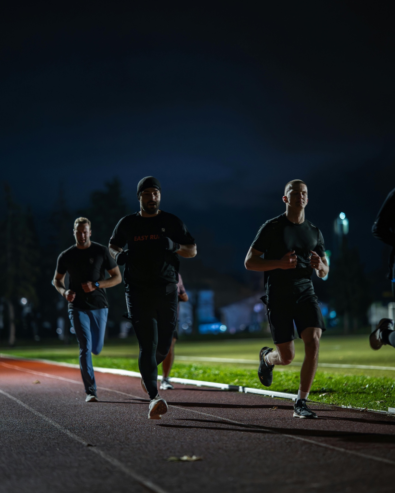 A pack of runners training together on a track at night